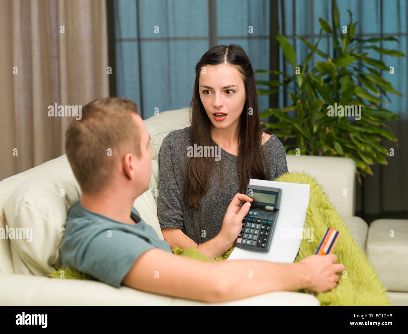 caucasian couple sitting on couch at home calculating payments Stock
