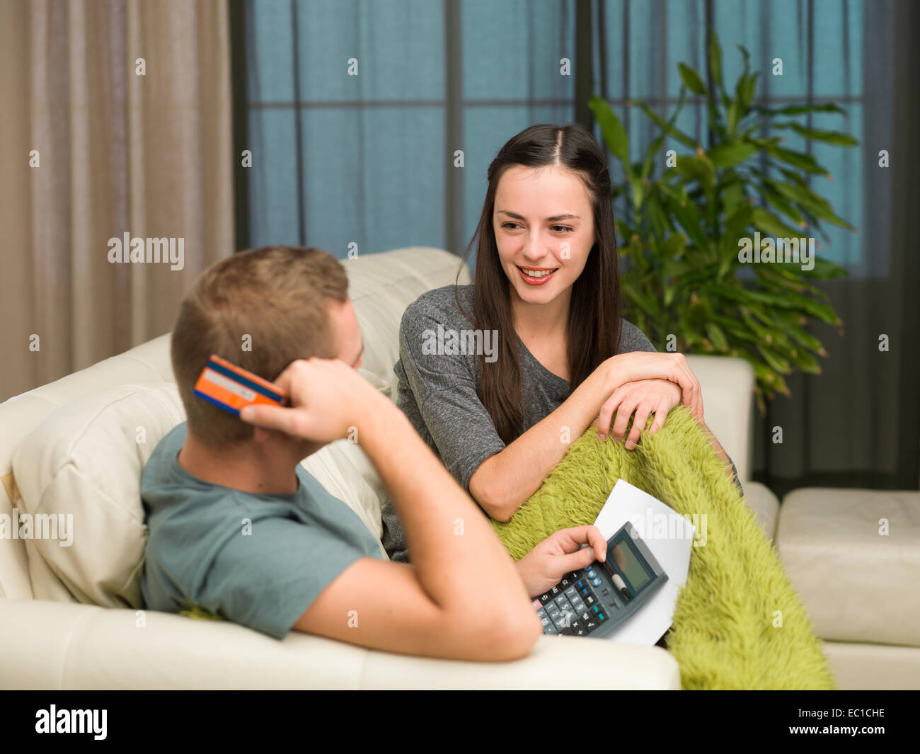 caucasian couple sitting on couch at home calculating payments Stock