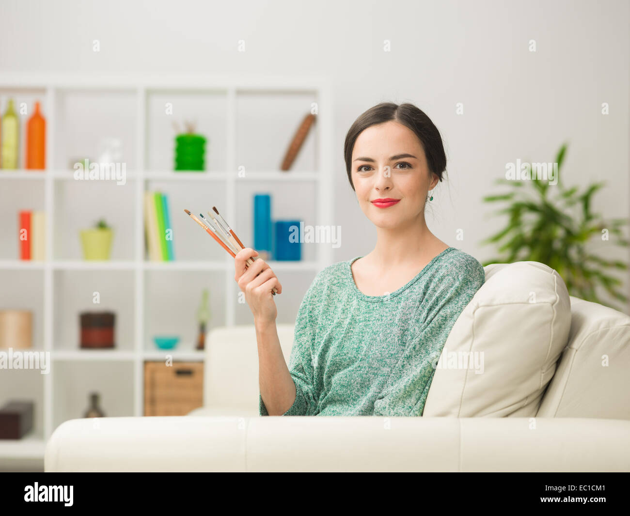 portrait of young beautiful caucasian woman sitting on sofa at home ...
