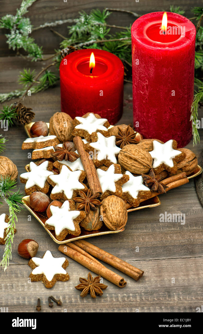 cinnamon cookies, nuts and spieces with christmas decoration red candles and pine branch. nostalgic home interior Stock Photo