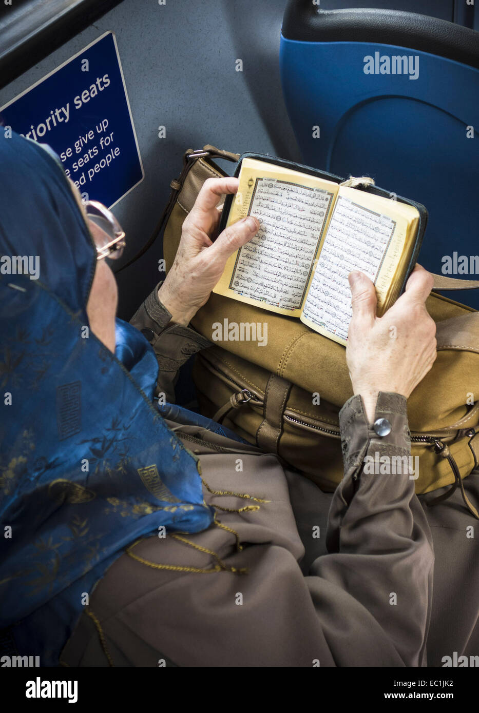 Moslem woman studying Koran on London bus. (Qur'an or Koran). Stock Photo