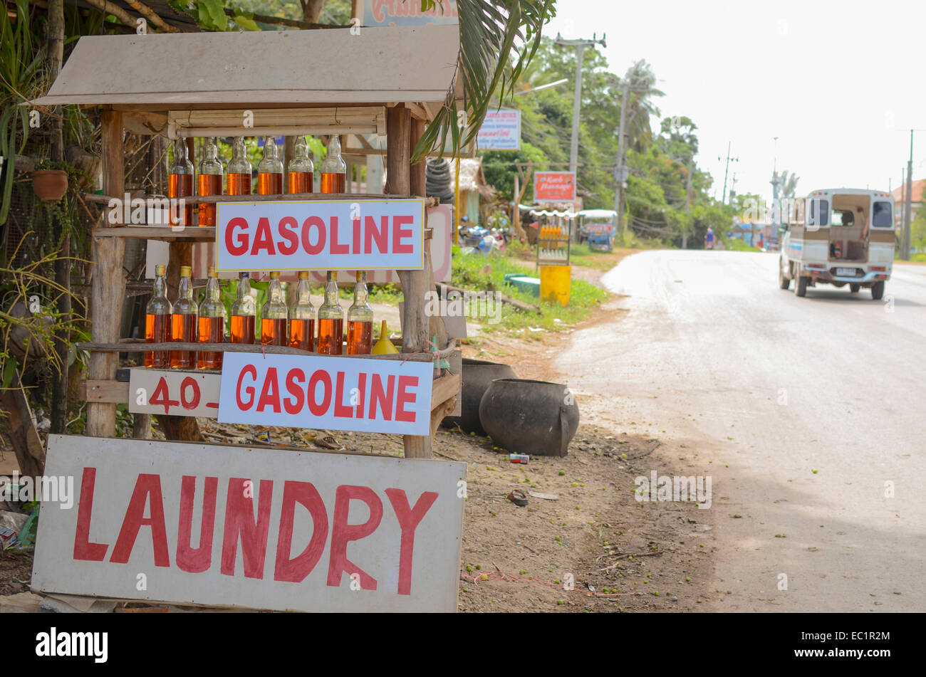 Thai roadside service station with gasoline bottles for sale and laundry sign, Koh Lanta, Thailand Stock Photo