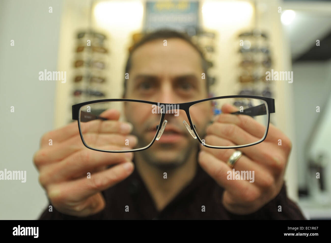 An opticians offers a customer new frames to try. Stock Photo