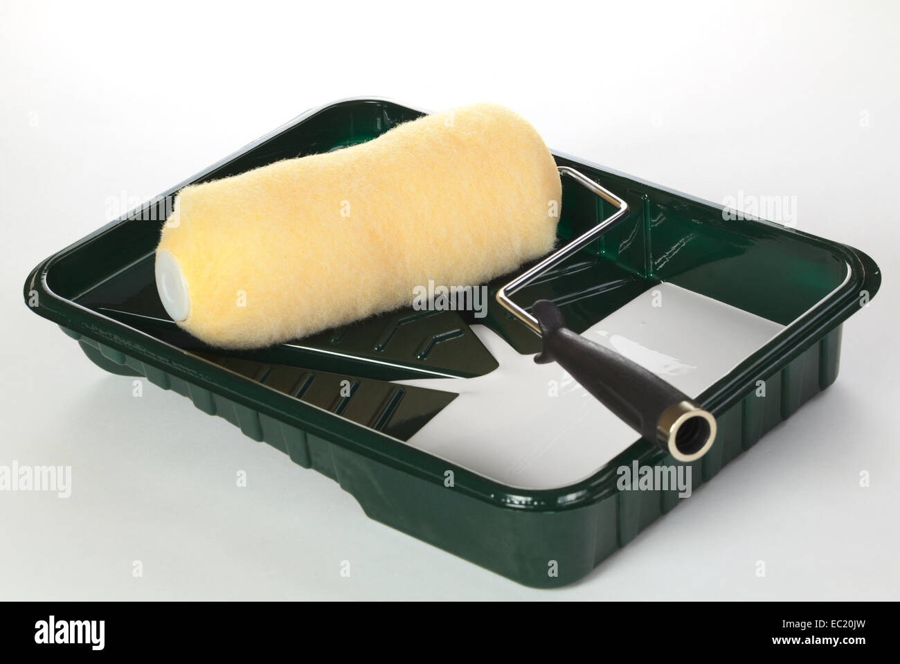 Paint roller in roller pan with some white paint photographed on white