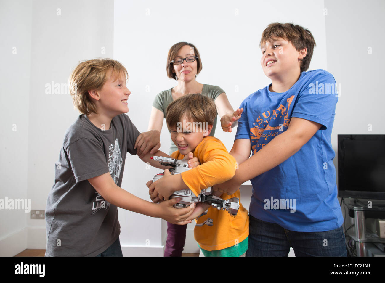 A mother trying to break up her children fighting at home Stock Photo