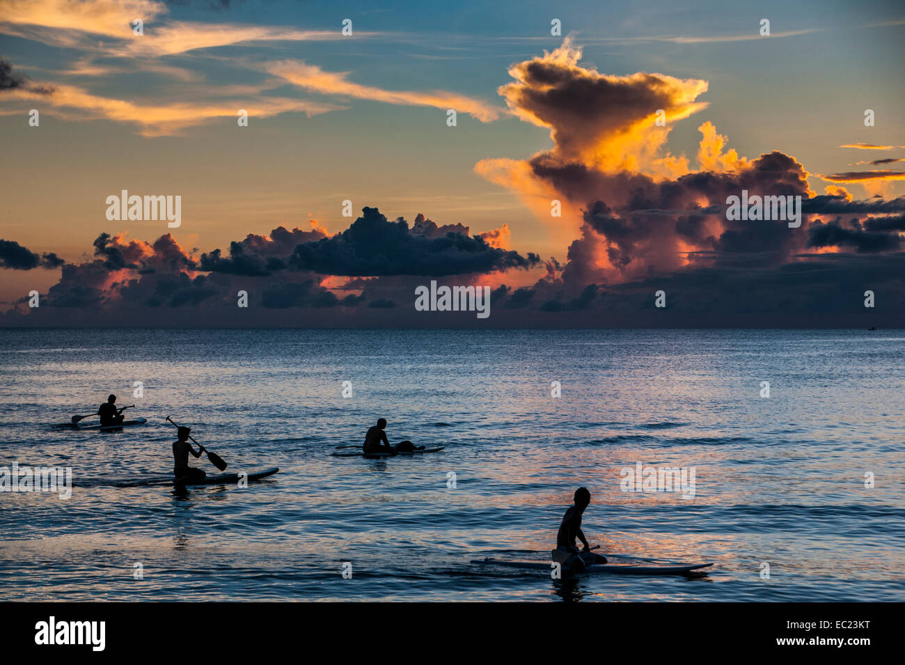 Surfers at sunset in Guam, US Territory, Central Pacific Stock Photo