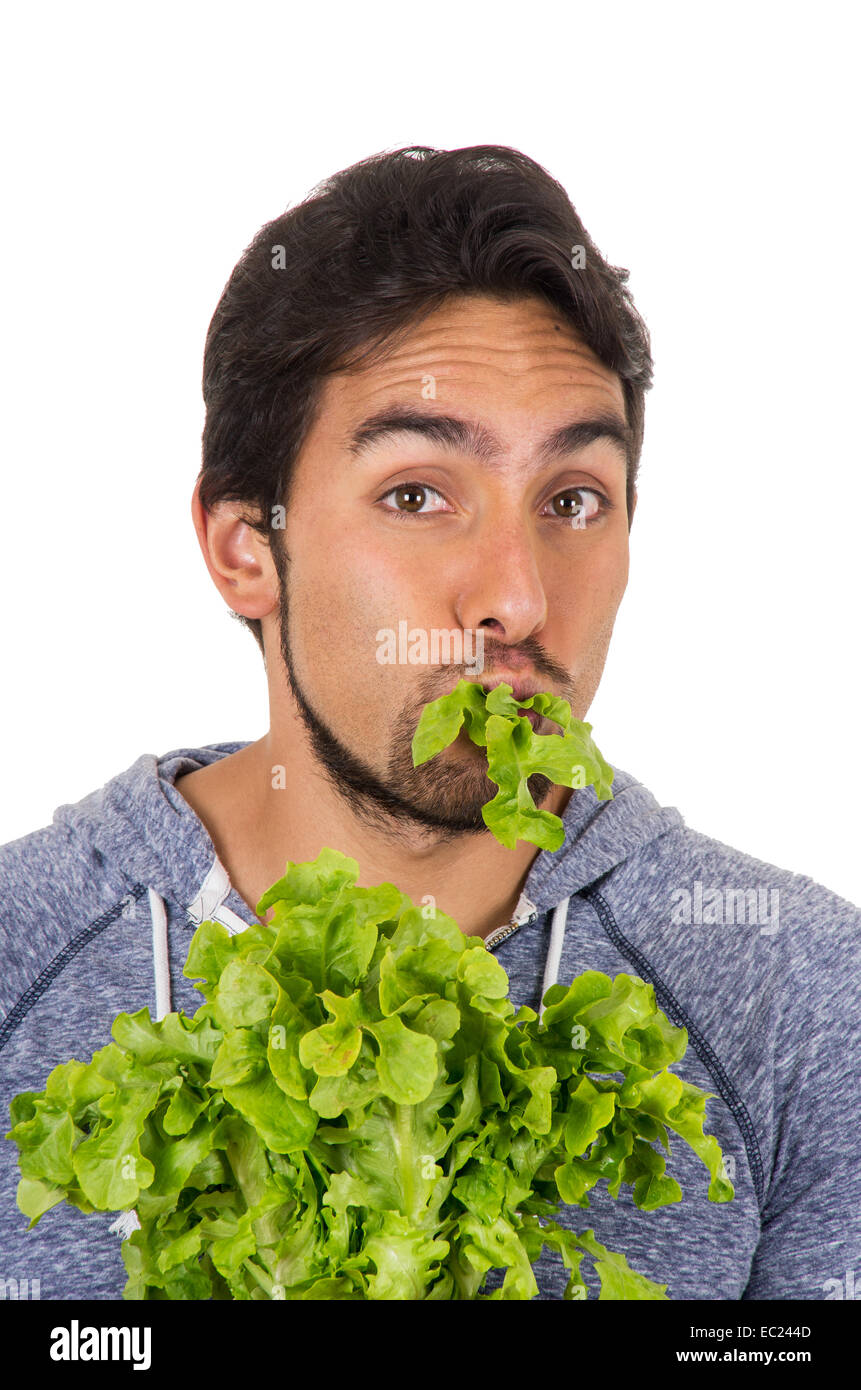 closeup portrait of handsome young man chewing fresh lettuce leaves Stock Photo