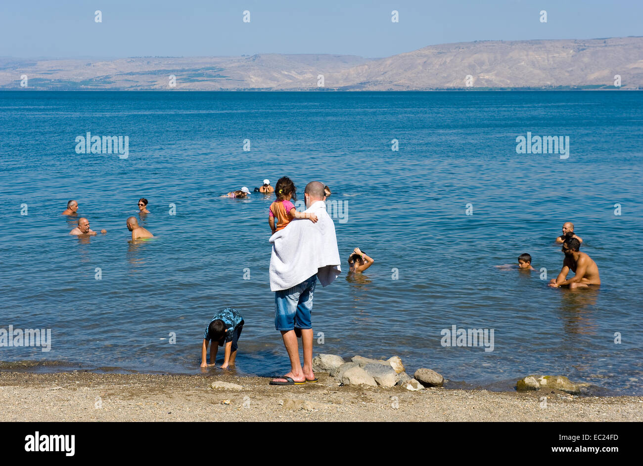 People are relaxing on the beach and in the sea of Galilee just south
