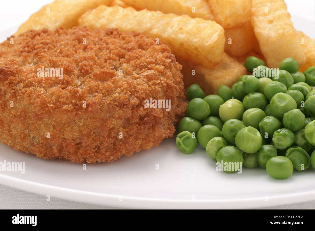 Fishcake made with crumbed fish and potato served with chips and peas Stock Photo