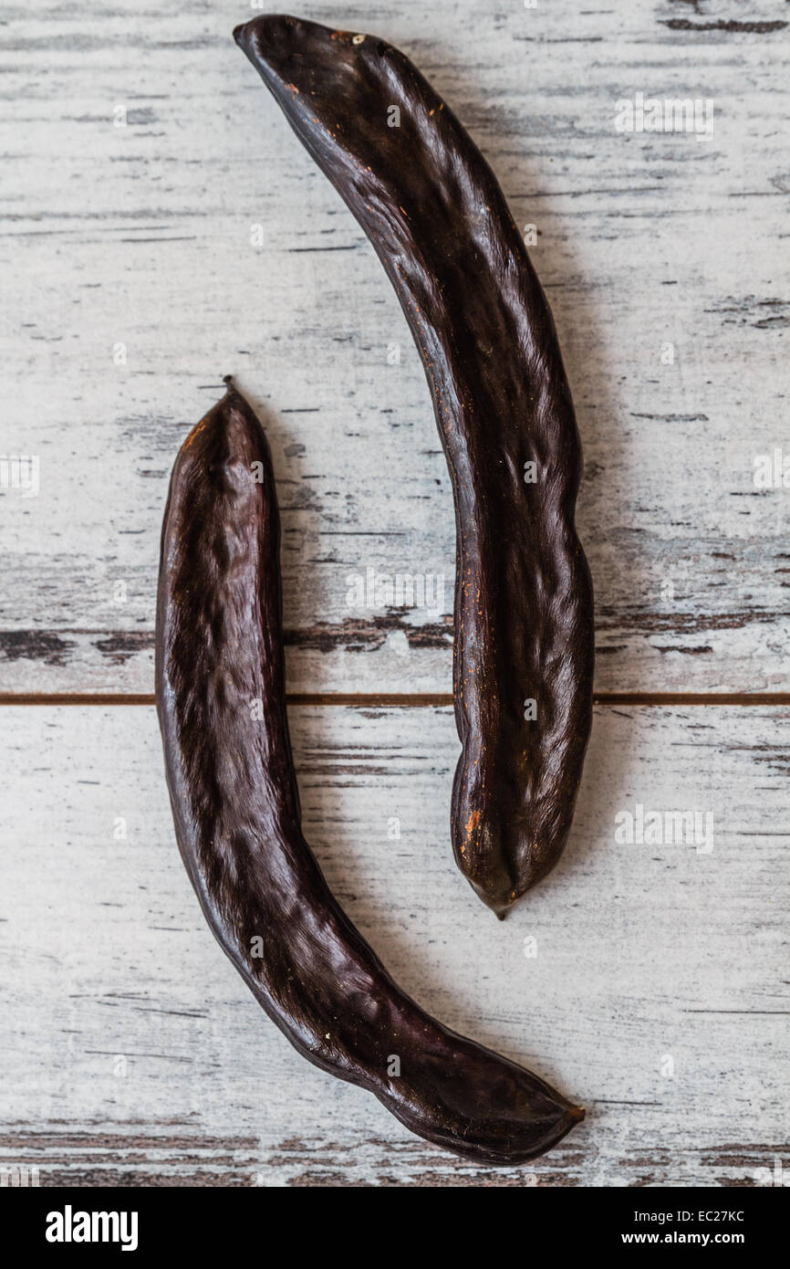 Dried carob pods on wooden white background Stock Photo Alamy