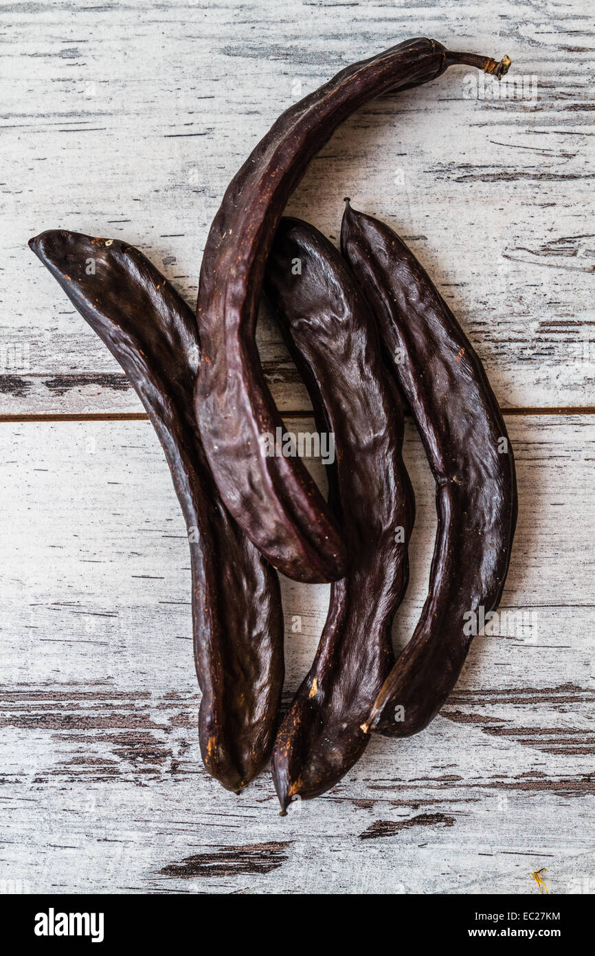 Dried carob pods on wooden white background Stock Photo Alamy