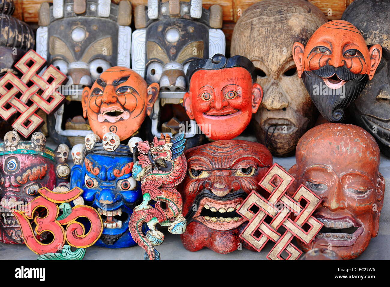 Colorfully painted carved wooden traditional masks representing various fierce demons-dragons-mythological beings-endless knot. Stock Photo