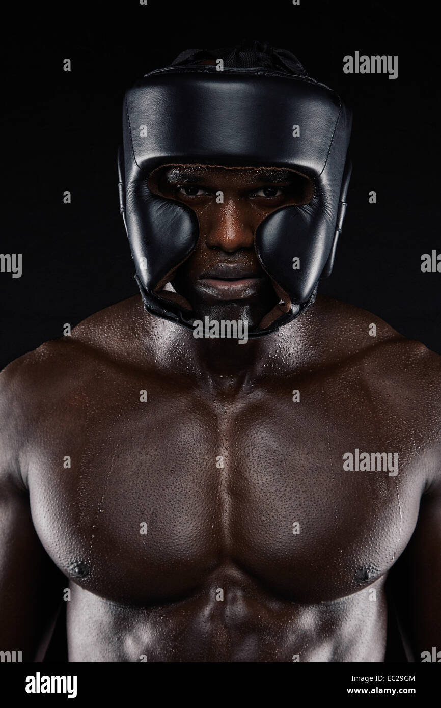 Portrait of African boxer wearing protective head guard against black