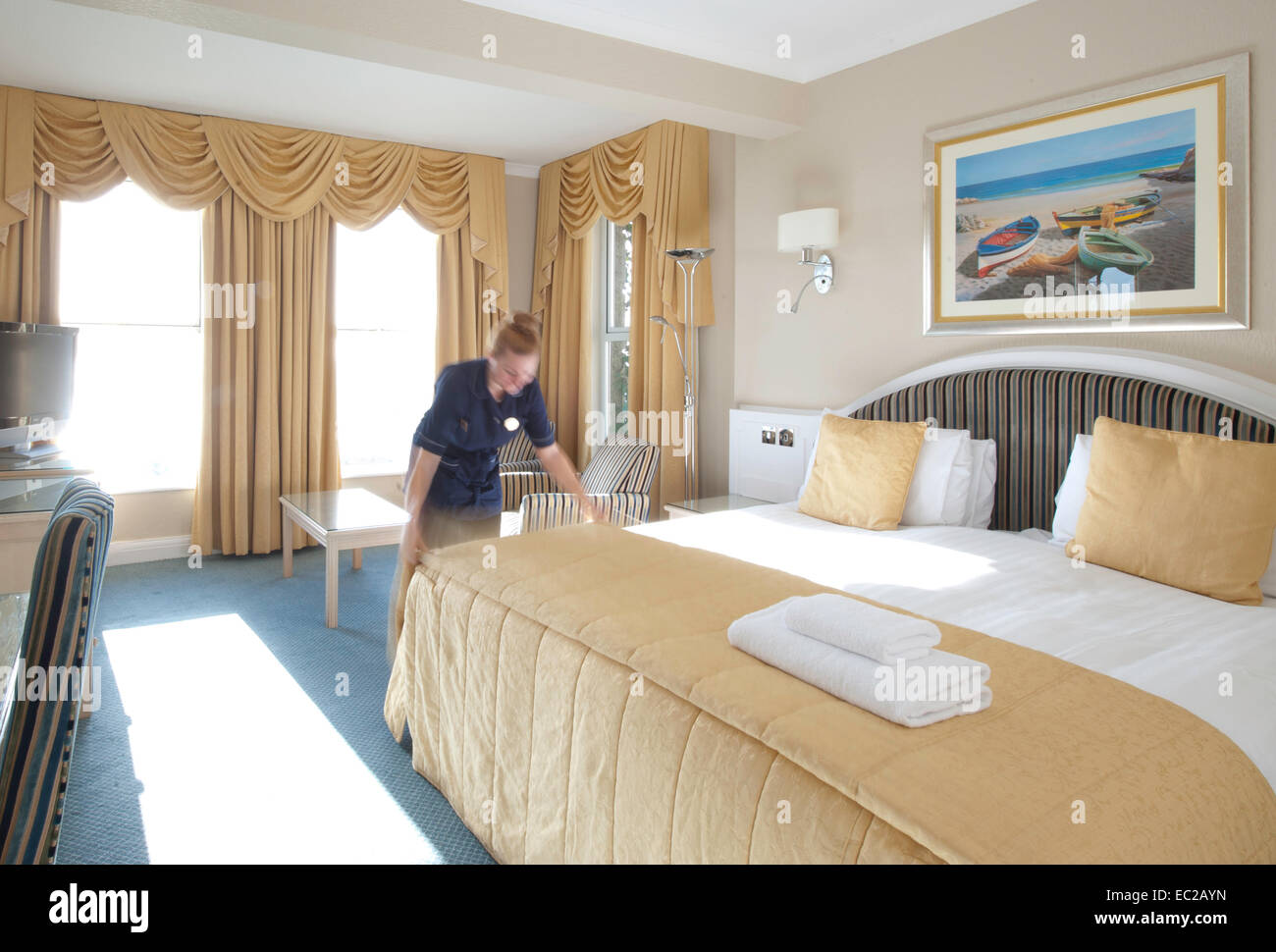 A housemaid making up a bed in a hotel Stock Photo