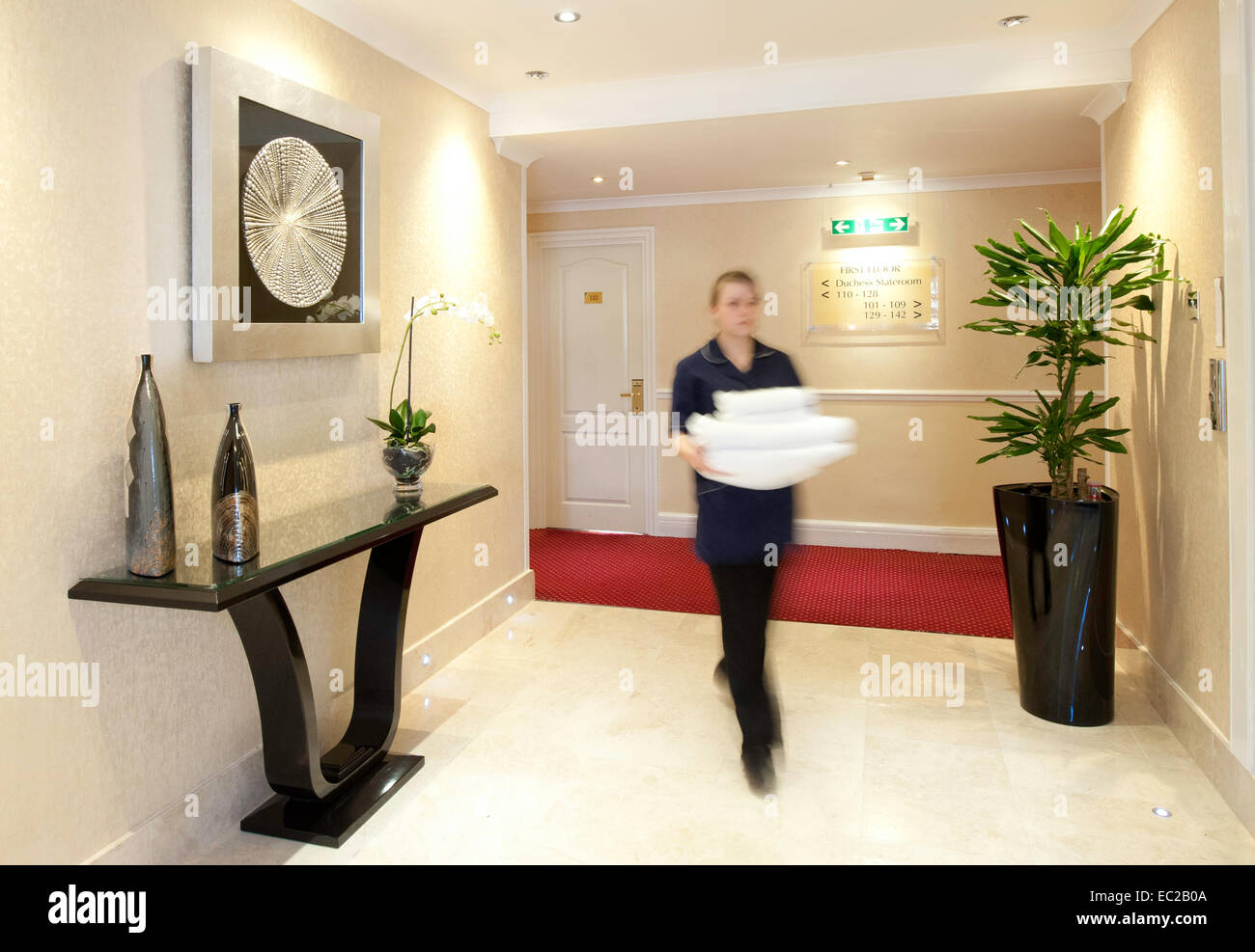 A hotel worker carrying towels in the lobby Stock Photo