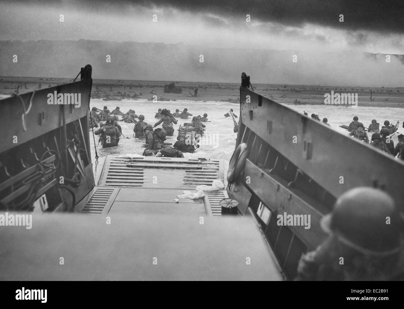 US soldiers from Company E, 16th Infantry, 1st Infantry Division wade ashore onto the Fox Green section of Omaha Beach from a Coast Guard operated LCVP landing craft during the D-Day invasion June 6, 1944 in Calvados, Basse-Normandie, France. American soldiers encountered the newly formed German 352nd Division when landing. During the initial landing two-thirds of the Company E became casualties. Stock Photo