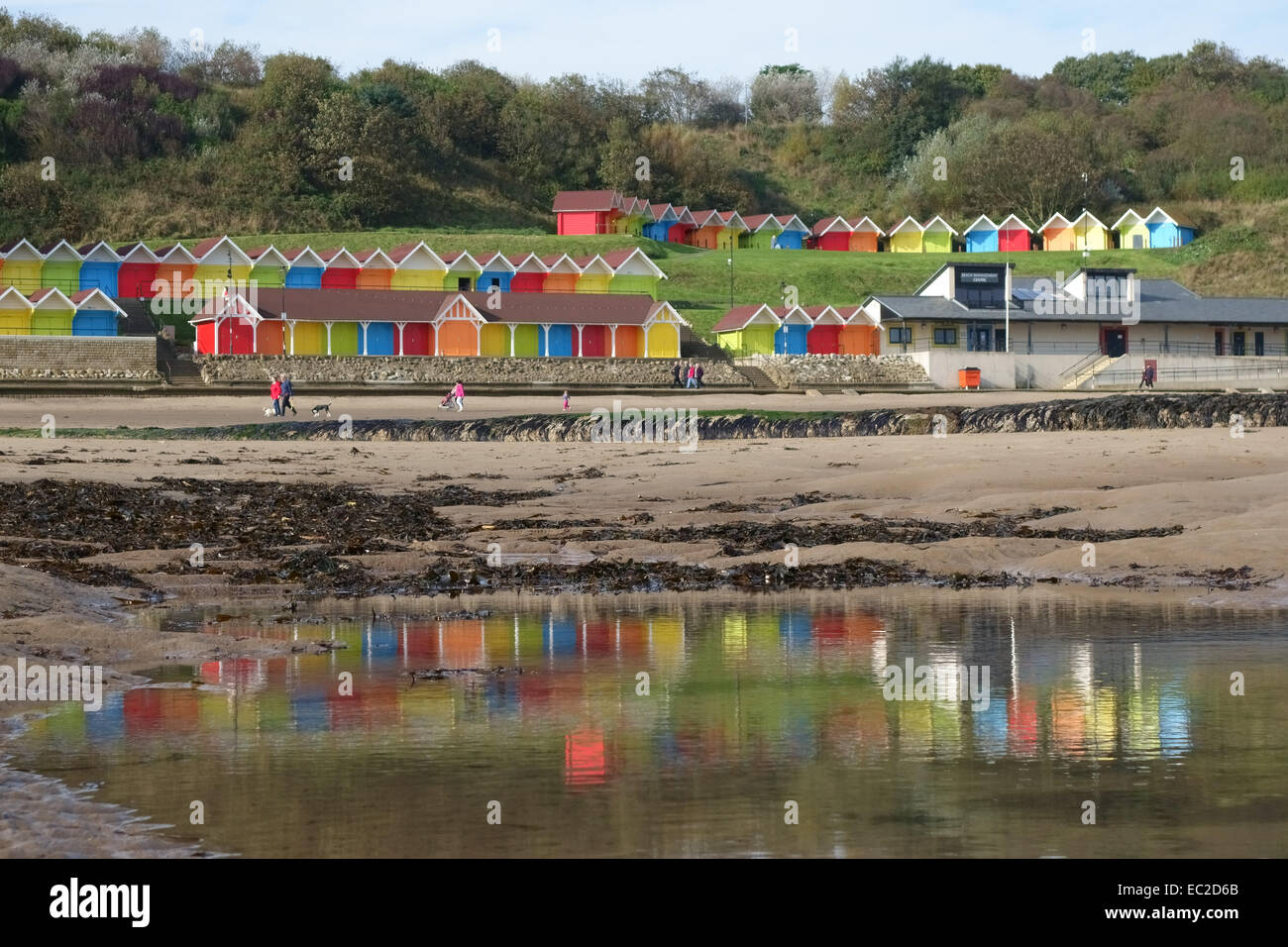 Colourful beach huts reflected in pools on the beach on Scarborough's North Bay at low tide, October Stock Photo