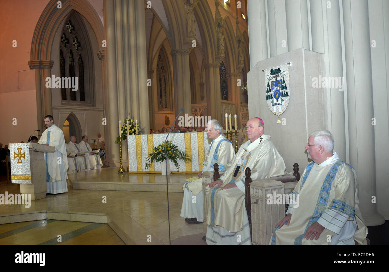 Salford, Greater Manchester, UK  8th December 2014 A priest reads the welcome of Bishop John Arnold at  the solemn mass of  his installation. He is the eleventh bishop of Salford replacing Bishop Terence Brain, who has retired after becoming the tenth bishop in 1997. Bishop Arnold was previously an auxiliary bishop in the Diocese of Westminster. New Roman Catholic  Bishop of Salford . Sitting in the centre is Archbishop McMahon of Liverpool, who welcomes Bishop Arnold to his new post. Credit:  John Fryer/Alamy Live News Stock Photo