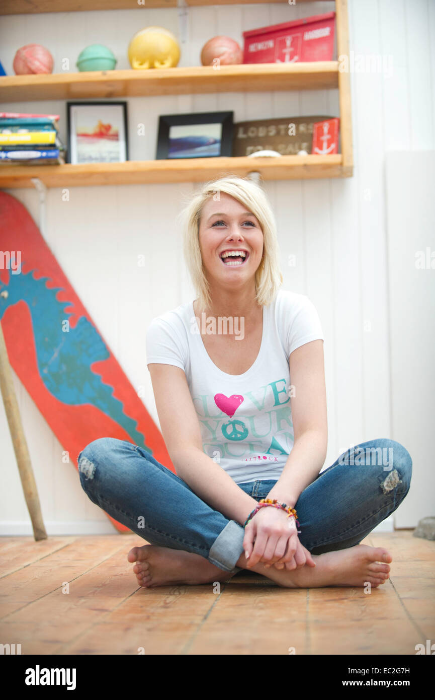 A blonde pretty girl smiling while sitting on the floor Stock Photo - Alamy