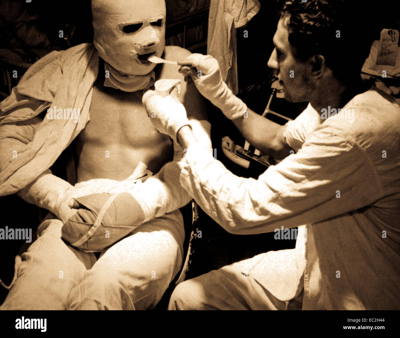 Pressure bandaged after they suffered burns when their ship was hit by a Kamikaze attack, men are fed aboard the USS SOLACE.  1945.  Attributed to Lt. Victor Jorgensen.  (Navy) Stock Photo