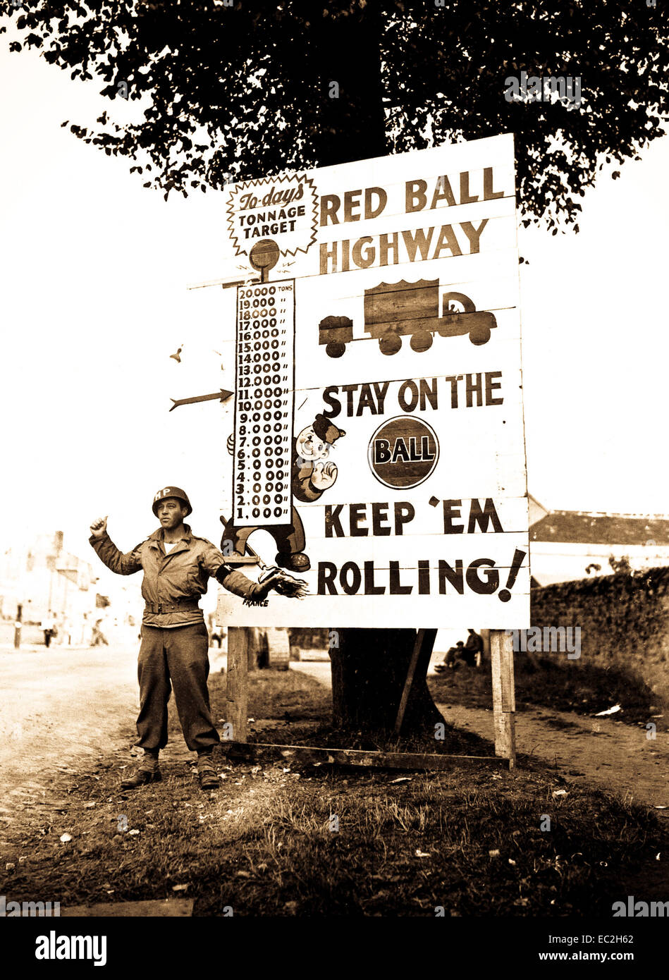 Corporal Charles H. Johnson of the 783rd Military Police Battalion, waves on a 'Red Ball Express' motor convoy rushing priority materiel to the forward areas, near Alencon, France.  September 5, 1944.  Bowen.  (Army) Stock Photo