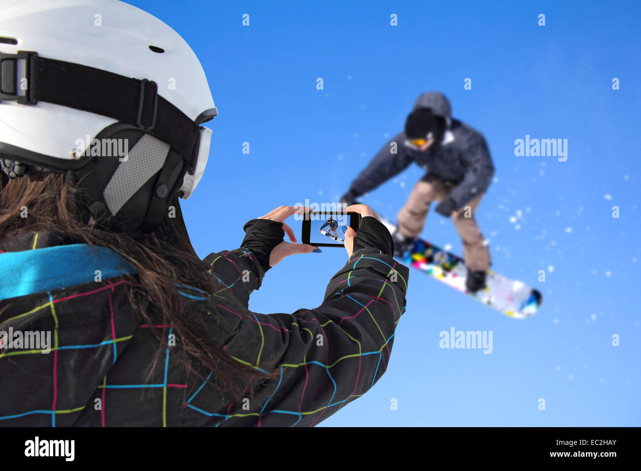 A young girl by mobile phone photographed of snowboarder jump Stock Photo