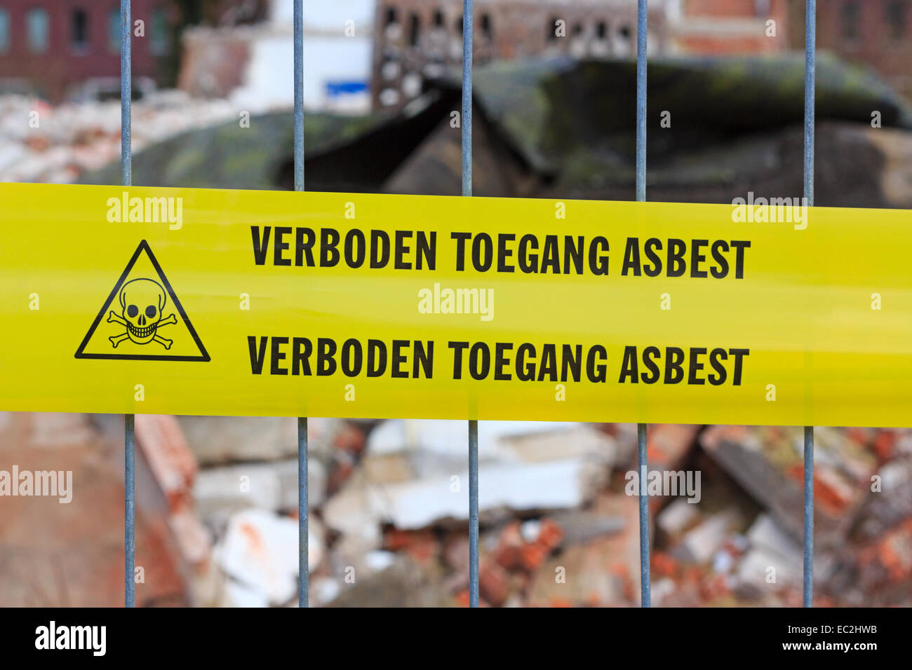 Yellow tape on fence with Dutch text 'no entry asbestos' in front of demolition site Stock Photo