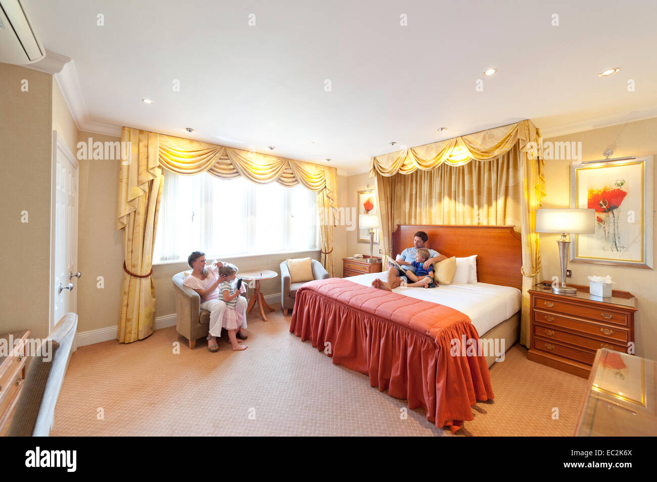 A family relaxing in a hotel bedroom Stock Photo