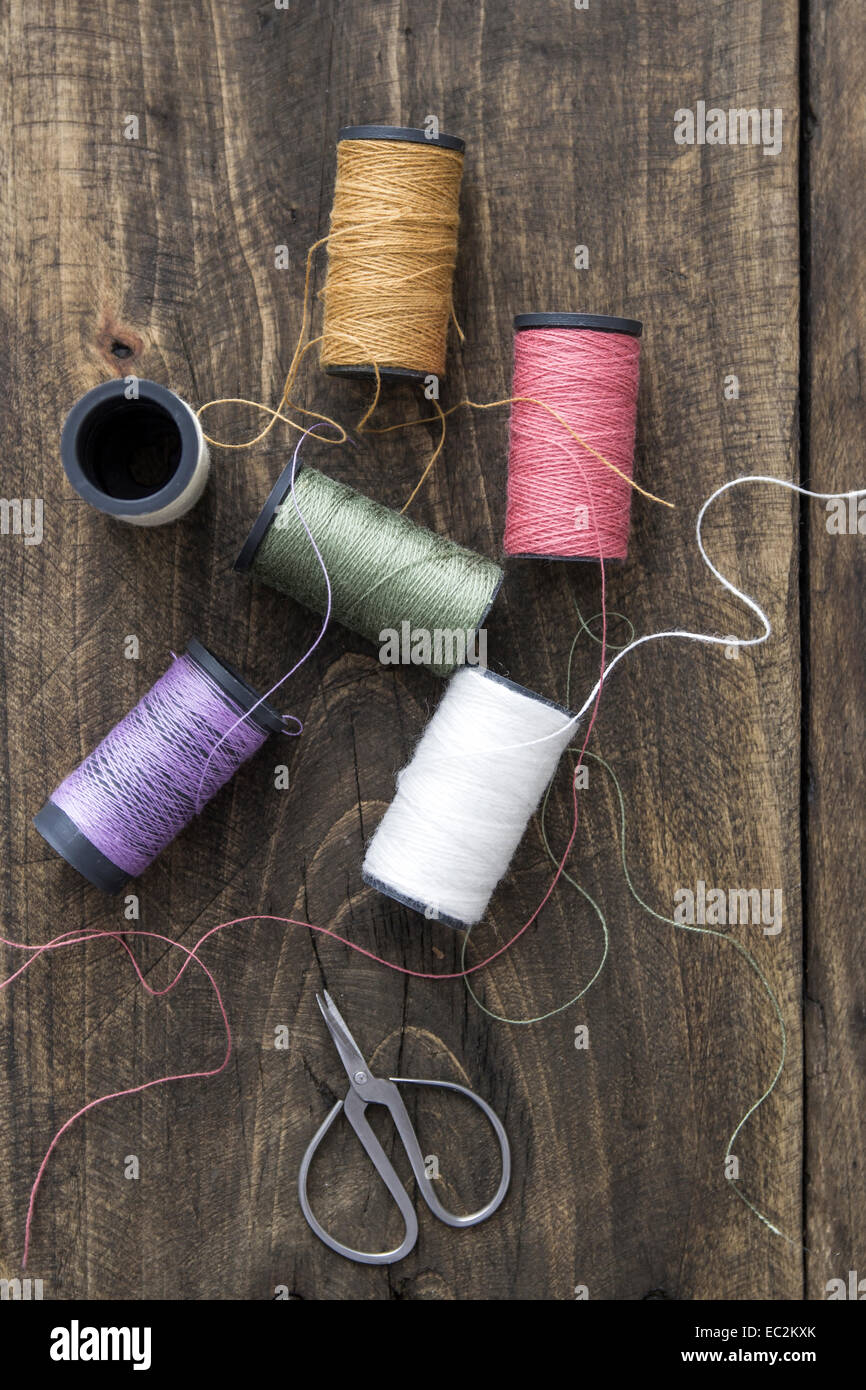 Sewing kit. Scissors and bobbins with thread on the rustic background