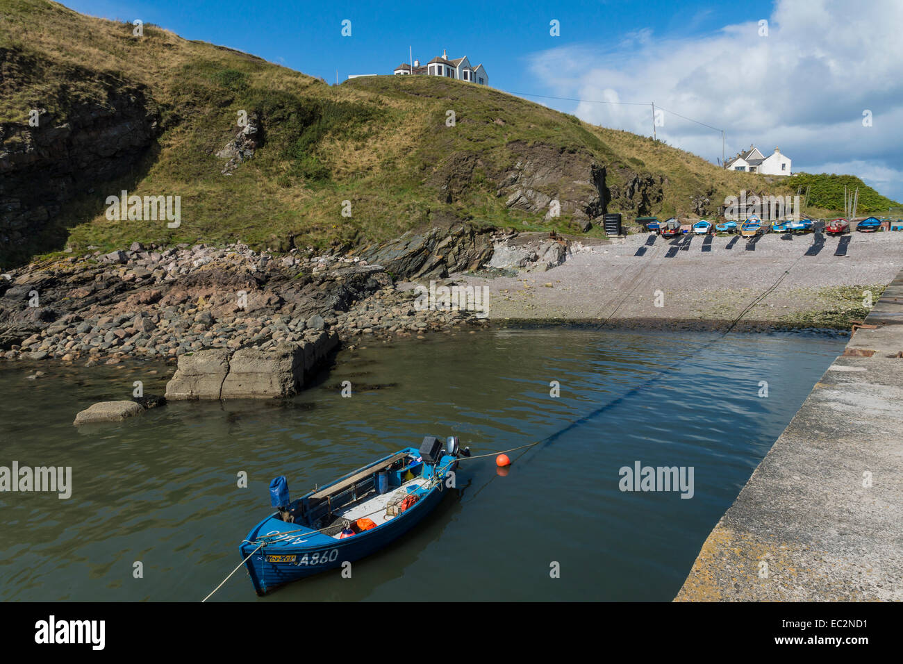 Cove harbour and blue fishing boat. Stock Photo