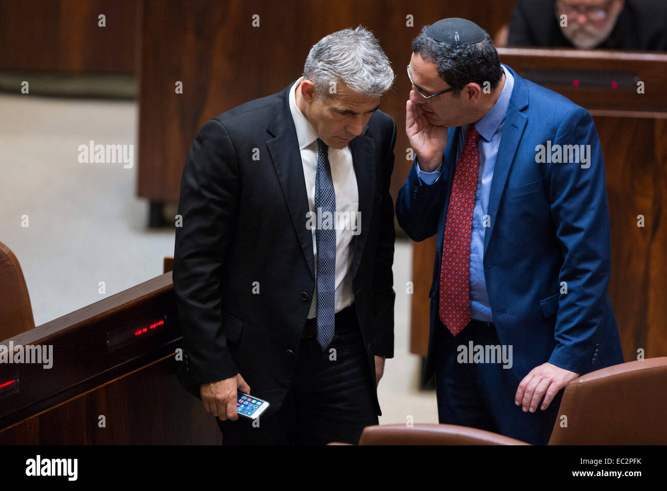 Jerusalem. 8th Dec, 2014. Former Israeli Finance Minister Yair Lapid (L) speaks with former Minister of Education Shay Piron during a vote on a bill to dissolve the Knesset (parliament) at the Knesset in Jerusalem, on Dec. 8, 2014. Israeli politicians voted in favor of dissolving the Knesset (parliament) on Monday night, and Israelis are expected to head to the polls next March. After two rounds of voting late on Monday, along with an initial vote on Wednesday, 93 members (out of 120) voted for early elections. © JINI/Xinhua/Alamy Live News Stock Photo