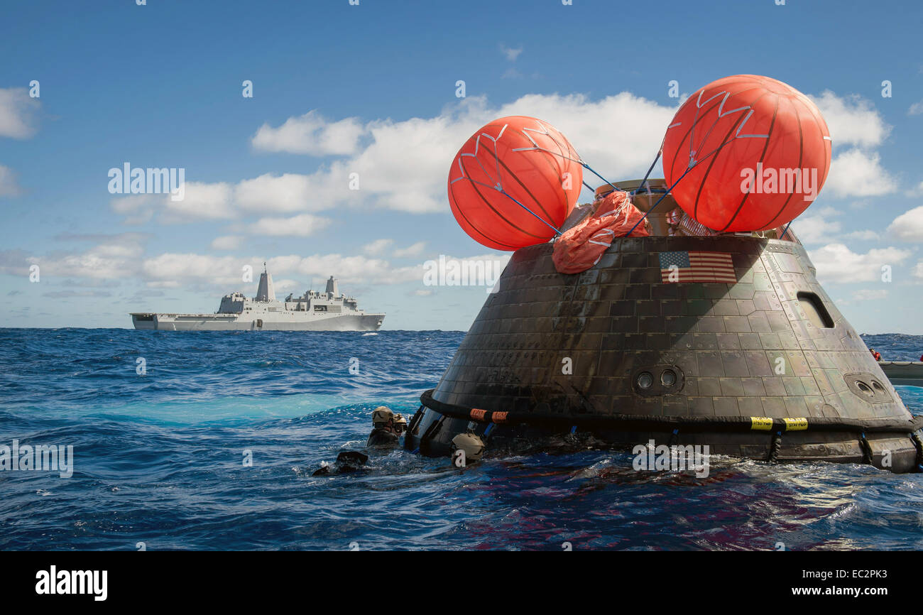 US Navy divers and sailors from the amphibious transport dock ship USS Anchorage attach a tow line to recover the NASA Orion space capsule after splash down following the first test flight December 5, 2014 in the Pacific Ocean. The Orion successfully blasted off atop a United Launch Alliance Delta IV Heavy rocket and orbited the earth 4 times before landing on target off the coast of California. Stock Photo