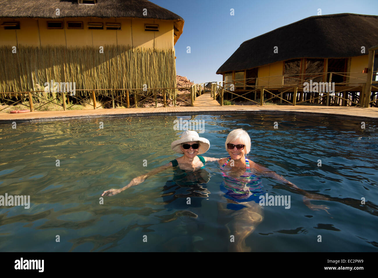 Africa, Namibia. Sossus Dune Lodge.  Namib Desert. Sossusvlei, Naukluft Park.  Two ladies relaxing in pool. Model Released Stock Photo