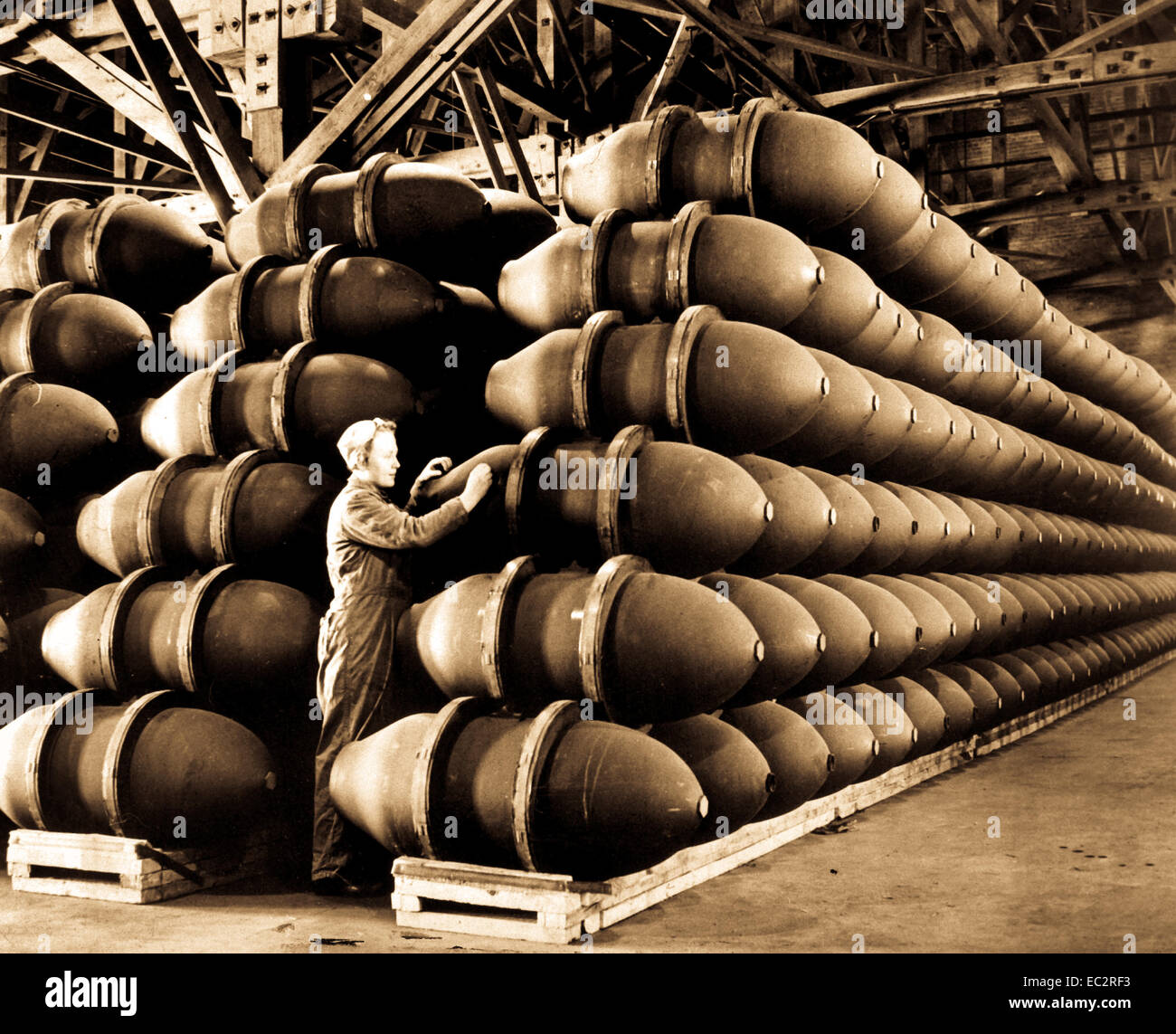 A woman war worker checks over 1,000 pound bomb cases before they are filled with deadly charges of explosives and shipped off to Allied bases and battlefronts all over the world.  Firestone Tire and Rubber Co.  Omaha, NE, ca.  May 1944. Acme.  (OWI) Stock Photo