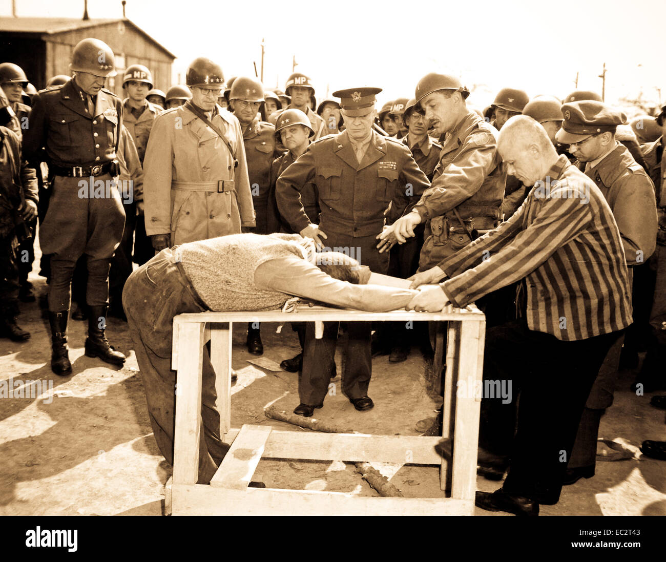 Gen. Dwight D. Eisenhower watches grimly while occupants of a German concentration camp at Gotha demonstrate how they were tortured by the Nazi sadists operating the camp.  Generals Bradley and Patton are at his right.  Germany, April 12, 1945.  Lt. Moore.  (Army) Stock Photo