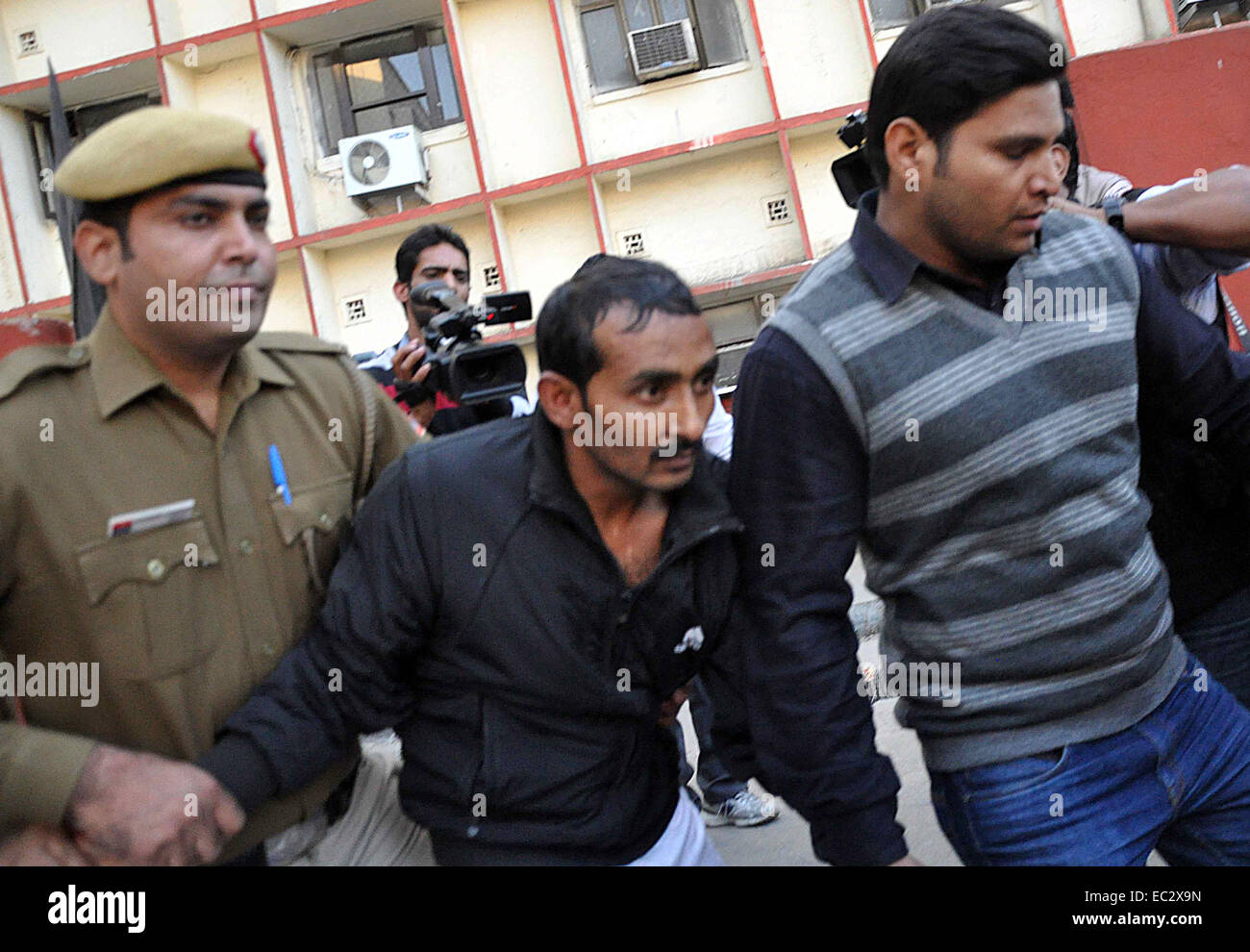 New Delhi, India. 8th Dec, 2014. Shiv Kumar Yadav (C), a taxi driver who was accused of raping, is escorted to the Tis Hazari Court by police officers in New Delhi, India, Dec. 8, 2014. The court has ordered Yadav be held for three days for police questioning over the allegation of his raping a 25-year-old female professional Friday night. © Stringer/Xinhua/Alamy Live News Stock Photo