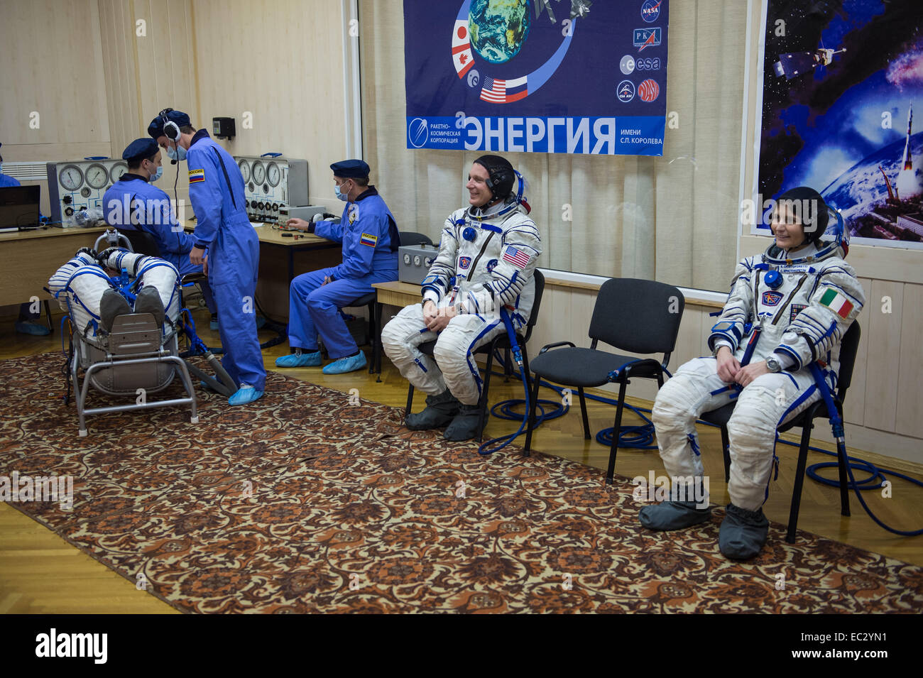 Expedition 42 Flight Engineers Terry Virts of NASA and Samantha Cristoforetti of the European Space Agency (ESA) wait while crewmate and Soyuz Commander, Anton Shkaplerov of the Russian Federal Space Agency (Roscosmos), has his Sokol suit pressure checked on Sunday, Nov. 23, 2014 at Building 254 in the Baikonur Cosmodrome in Baikonur, Kazakhstan. Launch of the Soyuz rocket is scheduled for the early hours of Nov. 24 and will carry Shkaplerov, Virts, and Cristoforetti into orbit to begin their five and a half month mission on the International Space Station. Stock Photo