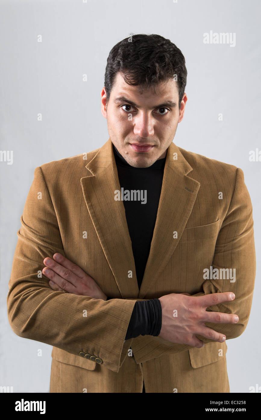 Young dark haired man wearing brown jacket and black pullover Stock Photo