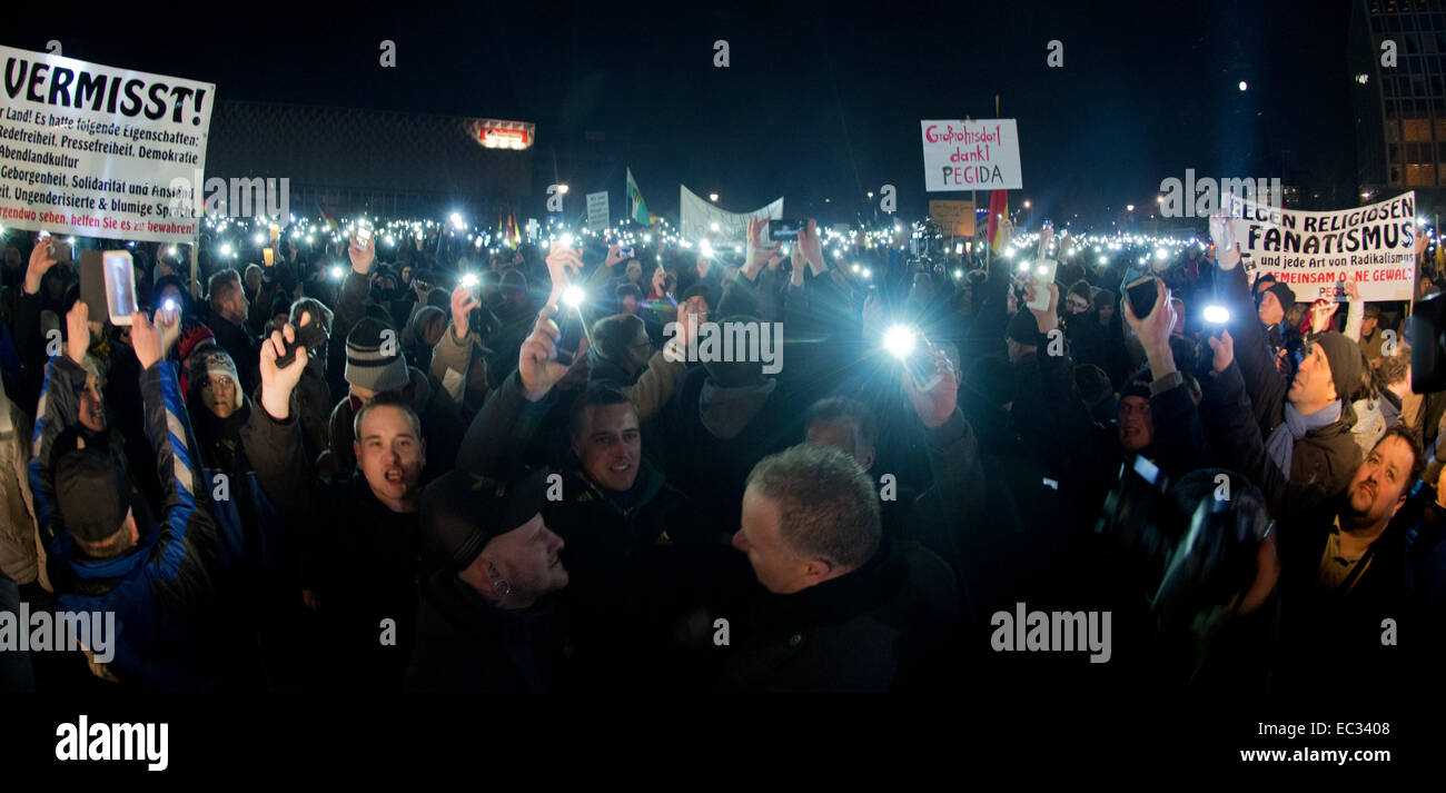 Dresden, Germany. 8th Dec, 2014. Participants of a Pegida rally (Patriotischen Europaeer gegen die Islamisierung des Abendlandes - Patriotic Europeans against Western Islamisation), hold up bannners and the glowing displays of their mobile phones in Dresden, Germany, 8 December 2014. The banners read 'Against religious fanatism and any kind of radicalism' (R), 'Großroehrsdorf thanks Pegida' (C). An alliance of representatives from churches, political parties and associations have staged a protest march against Pegida and intolerance in Dresden. Photo: Arno Burgi/dpa/Alamy Live News Stock Photo