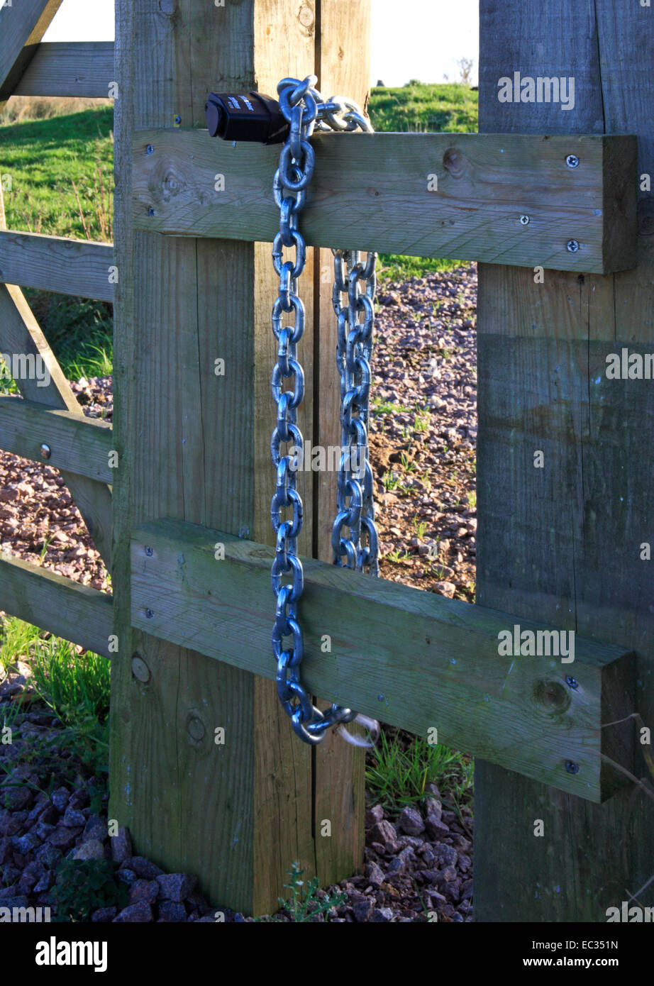 A padlock and chain hanging by a wooden gate Stock Photo Alamy