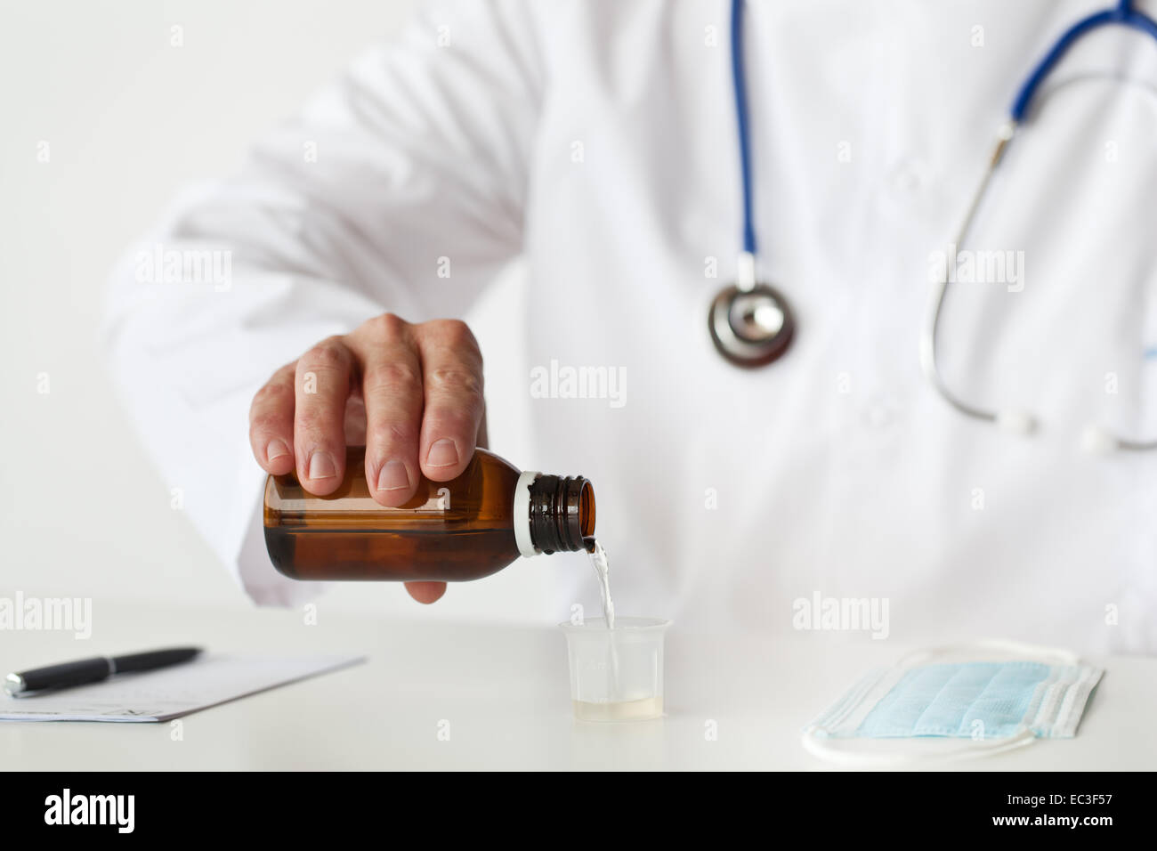 Doctor is filling a cup with cough syrup. Stock Photo