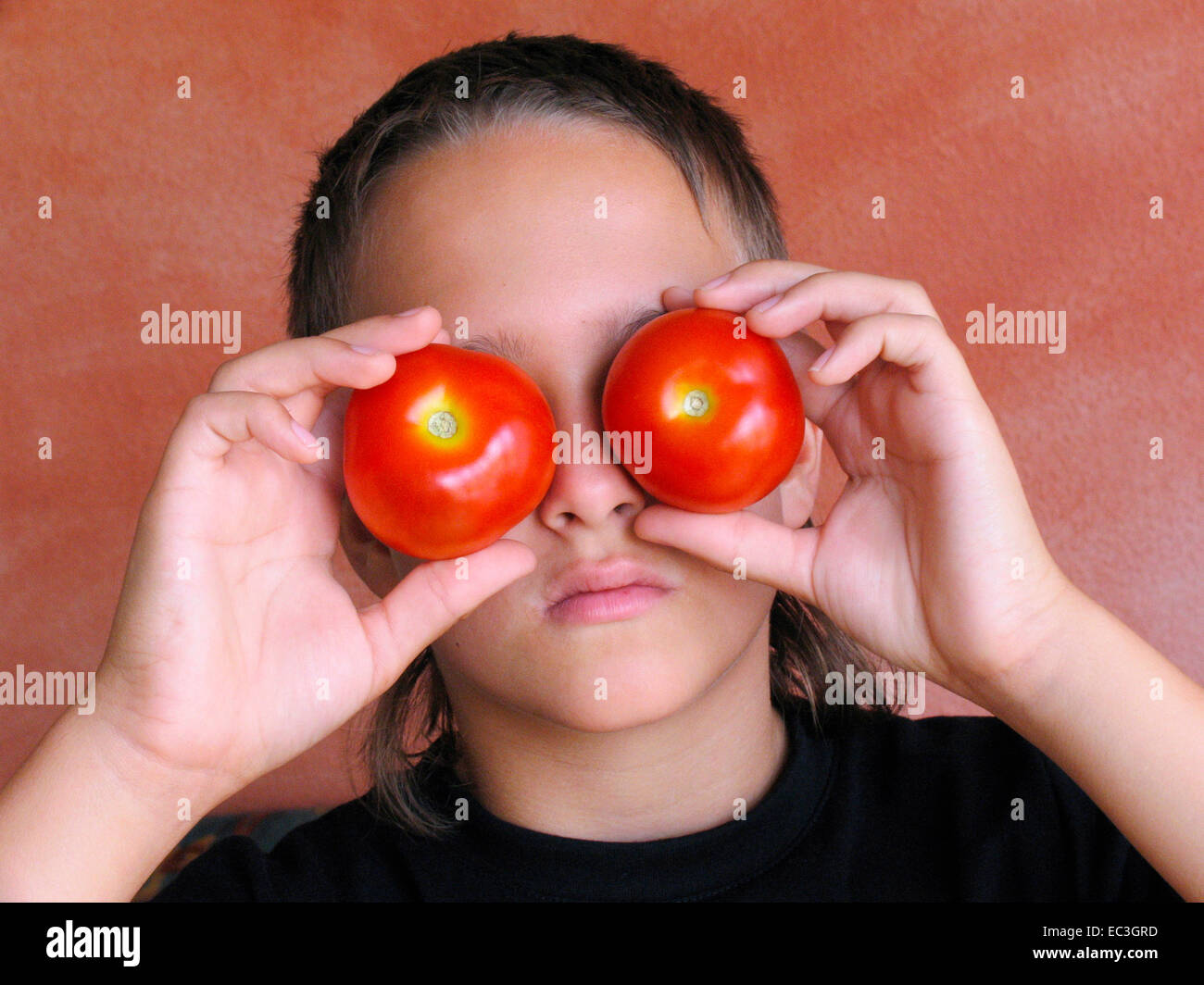 Young boy holding tomatoes in front of her eyes Stock Photo - Alamy