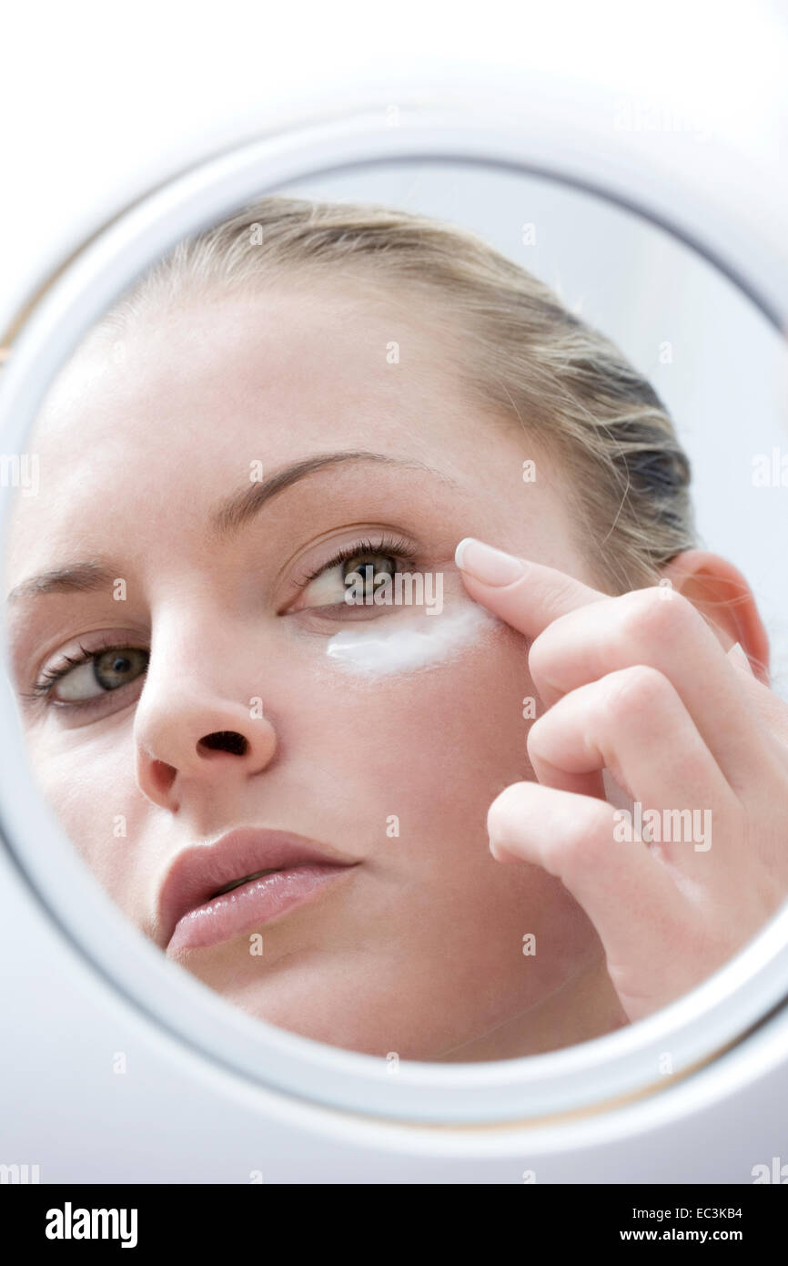 Woman applying Lotion on her Face Stock Photo