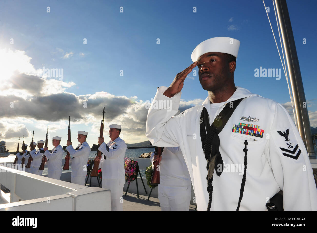 US Navy sailors salute during an ash scattering ceremony at the 73rd Anniversary commemoration at the Pearl Harbor memorial December 7, 2014 in Pearl Harbor, Hawaii. Pearl Harbor was attacked by Japanese forces on December 7, 1941. Stock Photo