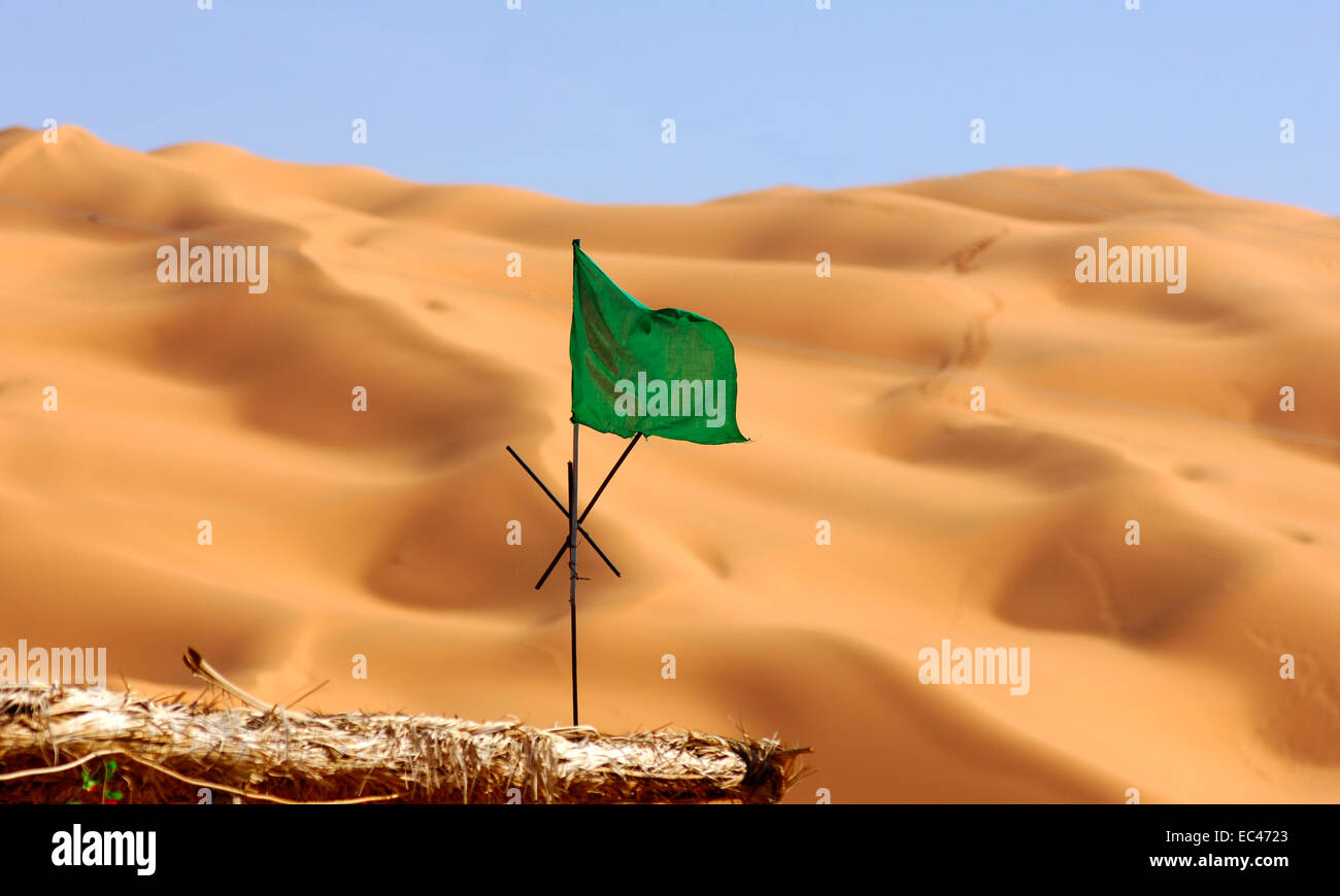 National flag of Libya fluttering over sand dunes of the Sahara desert