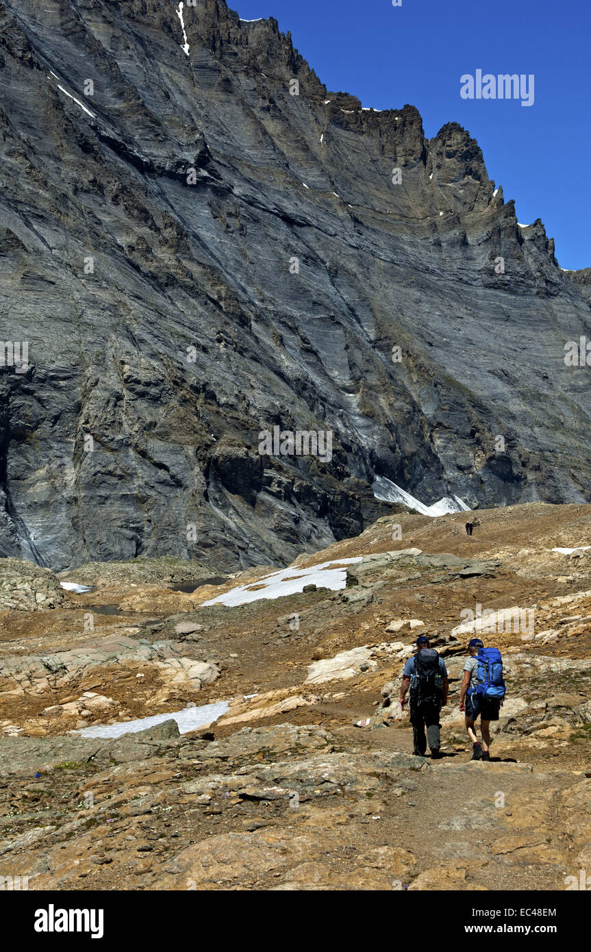 Hiker descending from the Loetschenpass at the foot of the Balmhorn peak, Bernese Alps, Bern, Switzerland Stock Photo