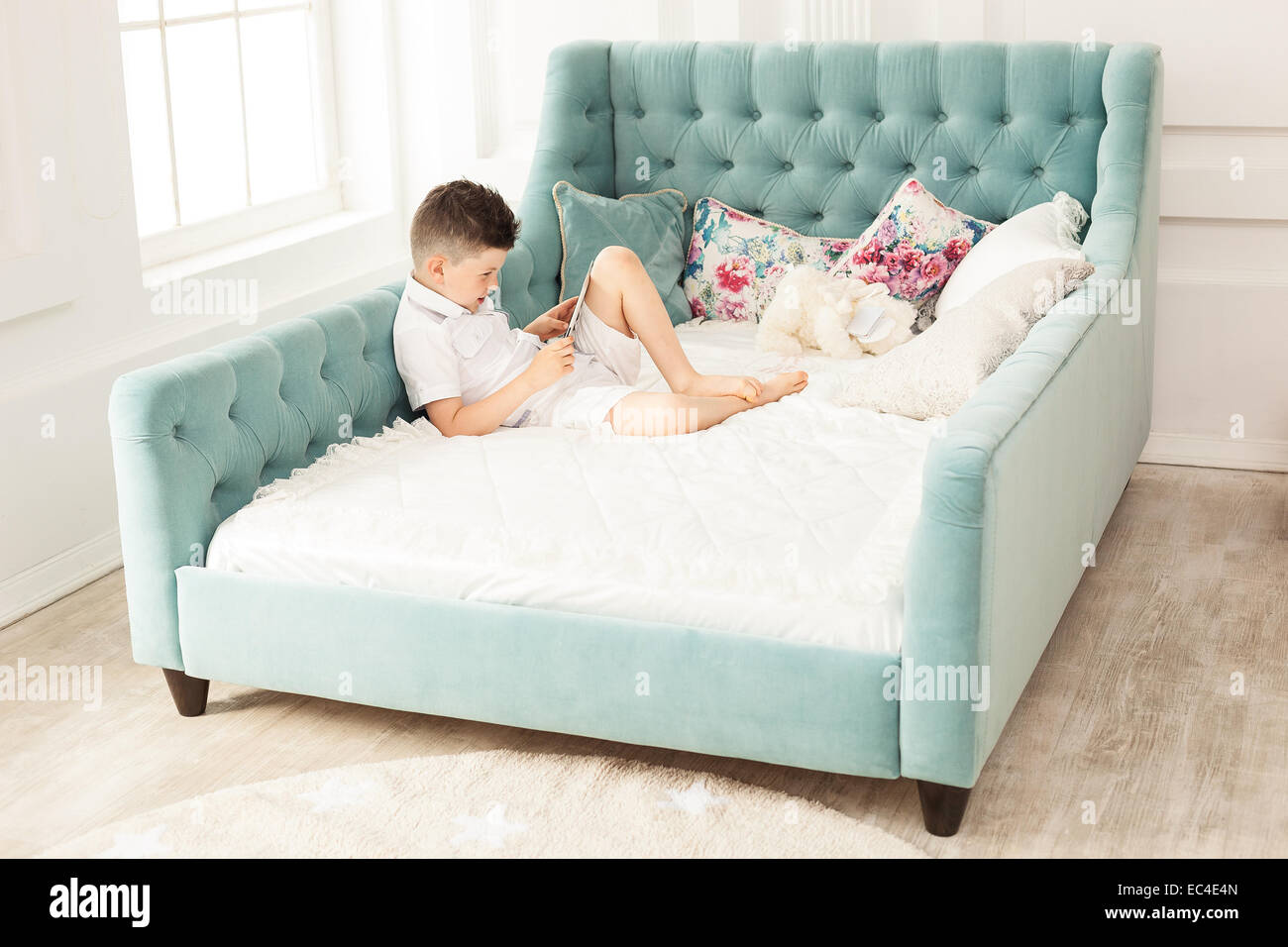 Young Boy Using Tablet Lying Down On Couch At Home Stock Photo