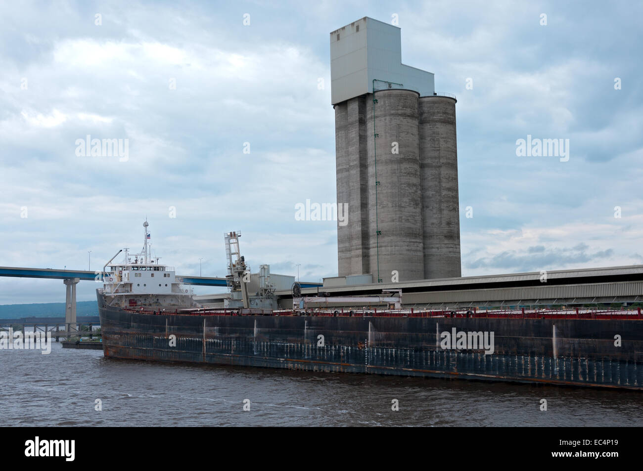 lake freighter shipping vessel on lake superior at receiving dock in duluth minnesota and grain silo behind Stock Photo