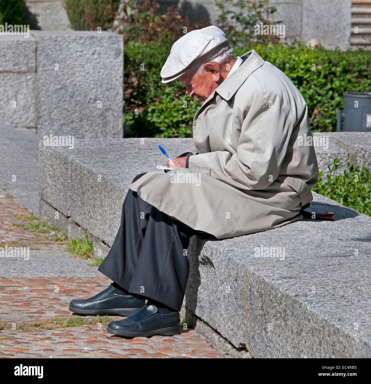 Old Man writing in the Sun in front of University  Salamanca old town center ( Castile and Leon ) Spain Spanish Stock Photo