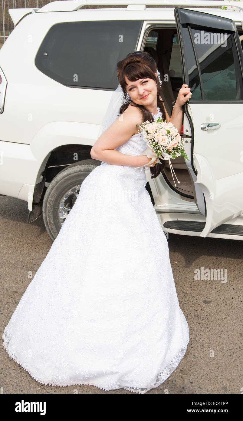 Bride with bouquet at the open car door Stock Photo